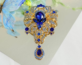 Broche vintage de cristal azul zafiro, broche colgante ornamentado en tono dorado.