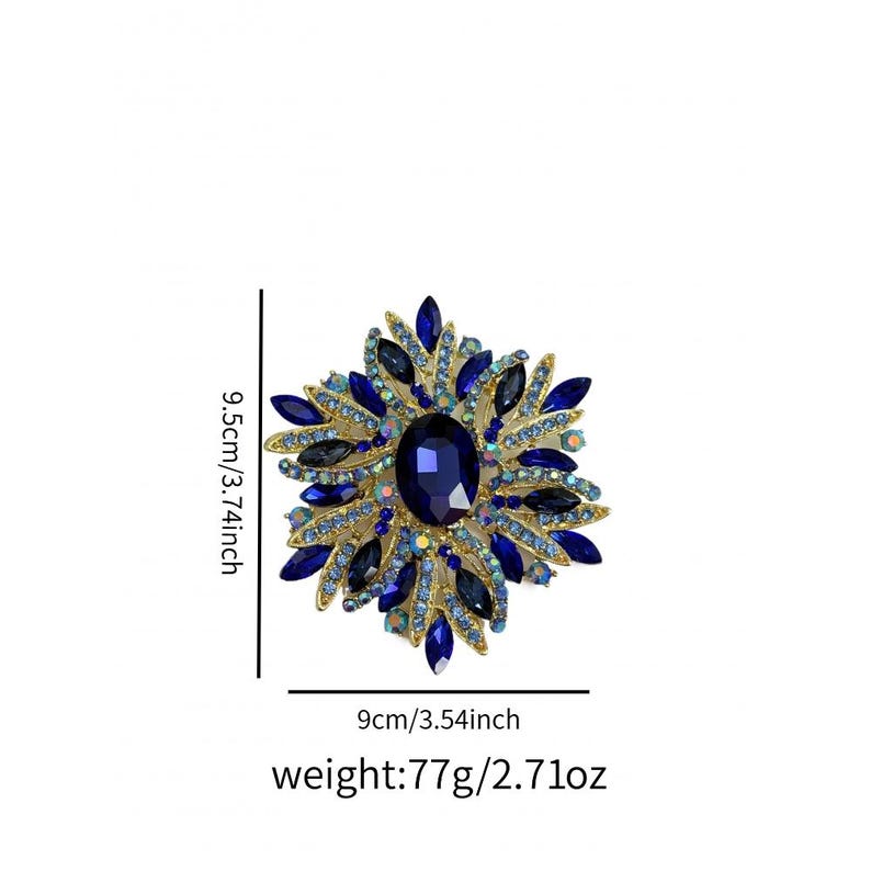 May include: A gold-toned brooch with a large, oval, dark blue gemstone at its center, surrounded by smaller blue and clear crystals. The brooch measures 3.74 inches in height and 3.54 inches in width, and weighs 2.71 ounces.
