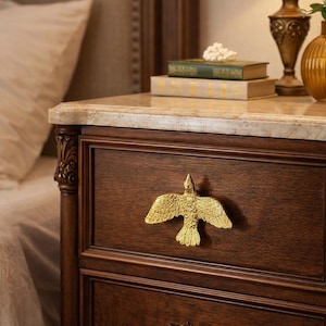 May include: A set of three ceramic mugs with a speckled, cream-colored glaze. Each mug features a different hand-painted design: a blue and green leaf, a yellow flower, and a red berry. The mugs have a simple, modern design.