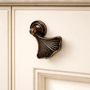 Könnte beinhalten: Ein Set aus drei Keramikbechern mit gesprenkelter, matter Oberfläche. Die Becher sind in Creme-, Hellgrau- und Dunkelgrautönen gehalten. Jeder Becher hat ein schlichtes, minimalistisches Design und einen abgerundeten Henkel.