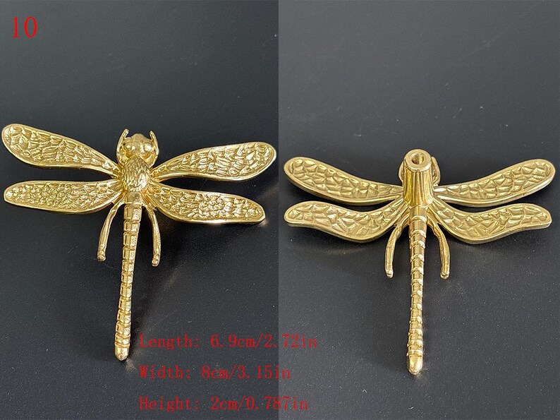 Puede incluir: Adorno de lib&eacute;lula dorado. La lib&eacute;lula tiene alas detalladas y un cuerpo segmentado. La longitud es de 6,9 cm, la anchura es de 8 cm y la altura es de 2 cm. La lib&eacute;lula se muestra sobre un fondo oscuro.