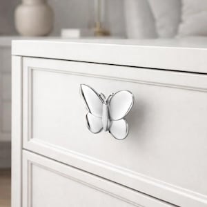 May include: A white ceramic mug with a black handle and the text "But First, Coffee" in a bold, black font. The mug is sitting on a wooden surface. The mug is approximately 4 inches tall.