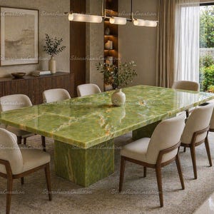 May include: A large, rectangular green onyx dining table with a matching base. Eight beige upholstered chairs with wooden frames surround the table. The room features a neutral color palette with natural light.