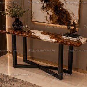 May include: A modern console table with a brown and white marble top and black metal legs. The table is decorated with a black vase, a decorative gold sculpture, and books. The table is a stylish addition to any home.
