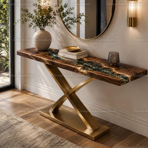 May include: A console table featuring a live-edge wood slab top with a central river-like inlay of dark resin and embedded stones. The table is supported by a gold-toned metal base with a crossed X-shaped design and a rectangular floor plate.