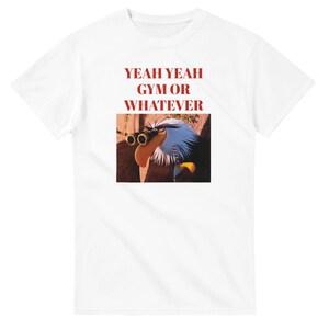 Könnte beinhalten: Weißes T-Shirt mit dem roten Text "YEAH YEAH GYM OR WHATEVER". Darunter befindet sich ein Cartoon-Bild eines Adlers mit Fernglas. Der Adler hat blaue und weiße Federn und einen gelben Schnabel.