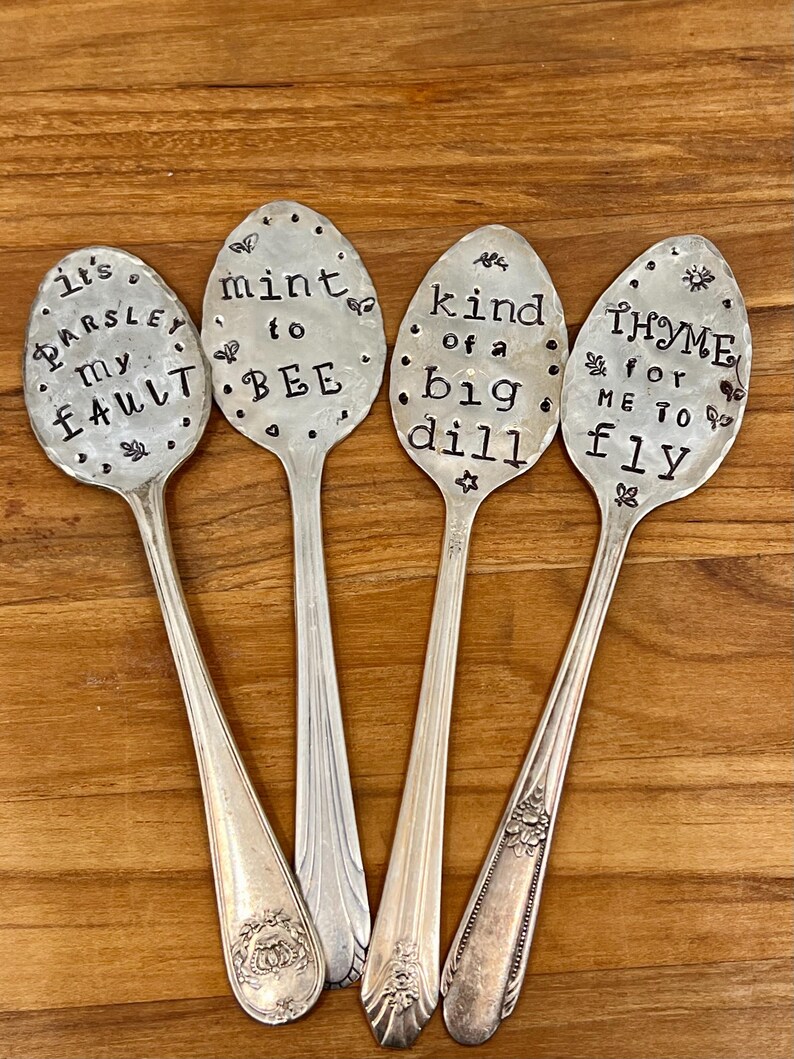 May include: Four silver spoons with engraved sayings. The spoons read "It's Parsley My Fault", "Mint To Bee", "Kind Of A Big Dill", and "Thyme For Me To Fly".