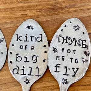 May include: Three silver spoons with black lettering. The spoons have the following text: "I'm kind of a big dill", "Thyme for me to fly", and "I'm at a loss for words".