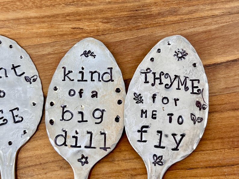 May include: Three silver spoons with black lettering. The spoons have the following text: "I'm kind of a big dill", "Thyme for me to fly", and "I'm at a loss for words".