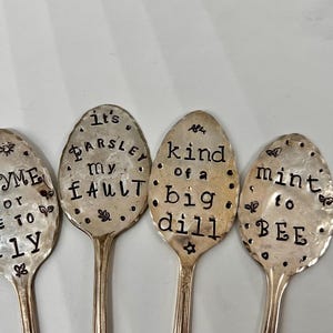 May include: Four silver spoons with engraved sayings about herbs. The spoons read "It's Parsley my Fault", "Thyme for me to fly", "Kind of a big dill", and "Mint to be".