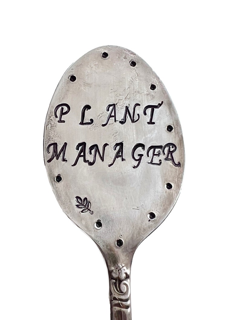 Garden marker made from recycled silver plate spoon flattened and hand stamped with the words ‘Plant Manager’ with decorative dots and stamps.