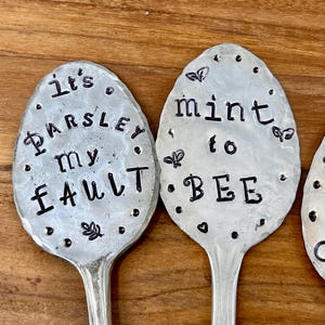 May include: Three silver spoons with black lettering. The spoons say "It's Parsley My Fault", "Mint to Bee", and "Kiss of the Bumblebee".