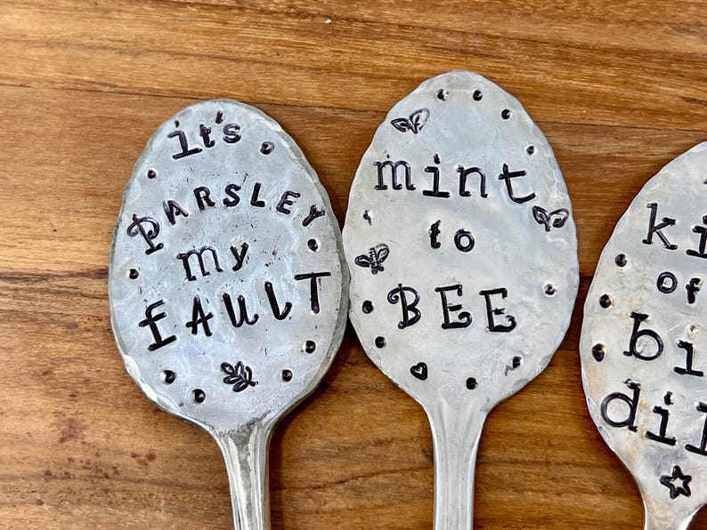 May include: Three silver spoons with black lettering. The spoons say "It's Parsley My Fault", "Mint to Bee", and "Kiss of the Bumblebee".