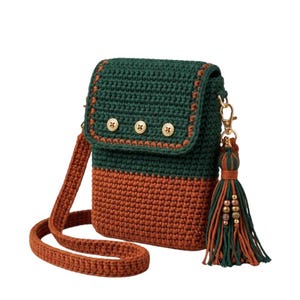 May include: A rectangular crochet crossbody bag featuring a dark green upper section and a rust-colored lower section. The flap is secured with three gold-toned buttons and the bag includes a matching strap and a decorative tassel with gold beads.