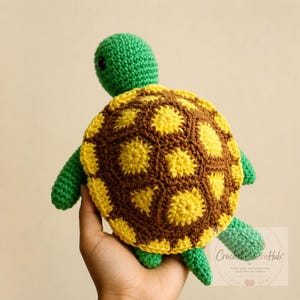 May include: A handmade crochet turtle toy featuring a bright green head and limbs with a textured shell composed of dark brown and vibrant yellow yarn segments. The shell displays a geometric pattern of yellow centers surrounded by brown borders.
