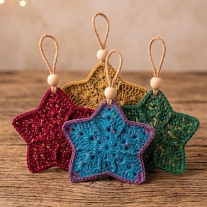 Peut inclure: Quatre décorations en forme d'étoile en fil crocheté de couleur rouge foncé, jaune moutarde, vert forêt et bleu vif. Chaque étoile comporte une petite perle en bois sur le dessus, fixée à une boucle en ficelle de jute pour la suspension.