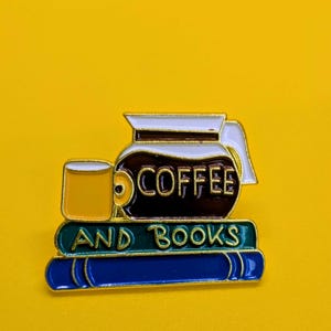 Peut inclure: Épingle émaillée représentant une cafetière, une tasse de café et deux livres. Les mots "COFFEE" et "AND BOOKS" sont affichés sur l'épingle. L'épingle a un code couleur jaune, marron, blanc, bleu et vert.