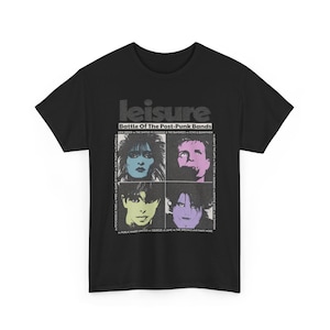 May include: Black t-shirt featuring the word "leisure" above a graphic that reads "Battle Of The Post-Punk Bands". The graphic includes four images of musicians and band names. The shirt is made of a soft material.