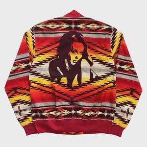 May include: A colorful bomber jacket with a geometric pattern in red, yellow, and orange. The back features a graphic of a woman. The jacket has a red collar, cuffs, and hem.