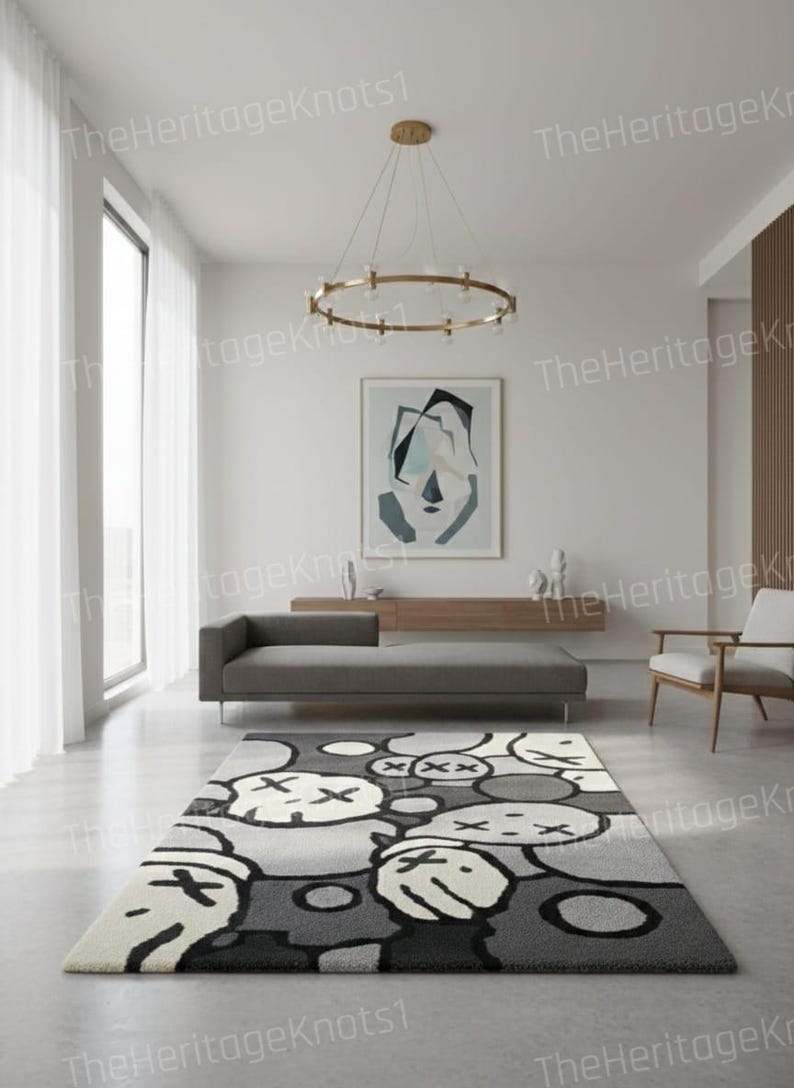 May include: A modern area rug with a repeating pattern of cartoon-like faces in shades of gray, black, and white. The rug is rectangular and placed in a contemporary living room setting. The room features a gray sofa, artwork, and a gold chandelier.