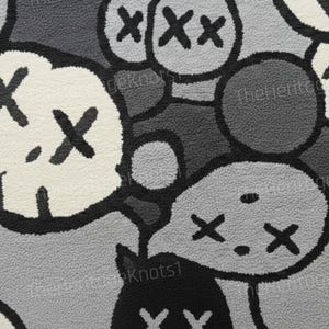 May include: Close-up of a rug with a repeating pattern of cartoon-like characters in shades of gray, black, and white. The characters have X-shaped eyes and mouths. The rug has a textured, plush surface.
