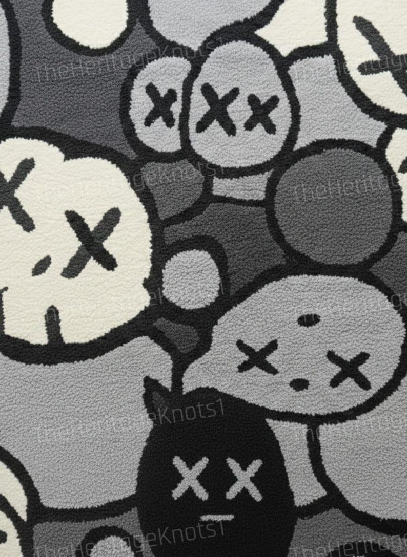 May include: Close-up of a rug with a repeating pattern of cartoon-like characters in shades of gray, black, and white. The characters have X-shaped eyes and mouths. The rug has a textured, plush surface.