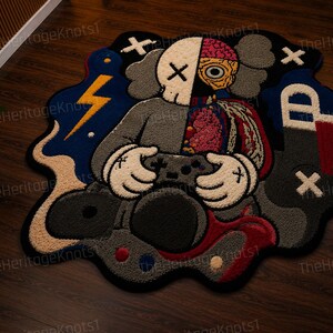 May include: A vibrant, cartoon rug depicting a character with a skull and brain design, holding a game controller. The rug's color palette includes blue, grey, and red, with a lightning bolt and other graphic elements.