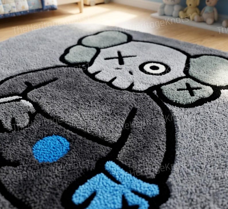 K&ouml;nnte beinhalten: Grauer Pl&uuml;schteppich mit einem Cartoon-Charakter-Design. Der Teppich hat einen grauen Hintergrund mit einer gro&szlig;en Figur in Grau-, Schwarz- und Blaut&ouml;nen. Die Figur hat kreuzf&ouml;rmige Augen und einen runden blauen Punkt.