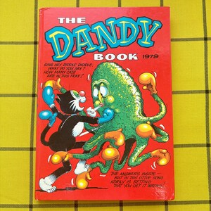 May include: A red hardback book titled The Dandy Book 1979. The cover features a black and white cat wearing blue boxing gloves fighting a green, multi-armed creature wearing yellow boxing gloves. Text on the cover includes a short poem.
