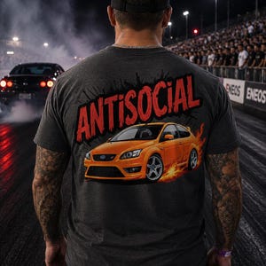 May include: A charcoal grey t-shirt featuring a graphic print on the back. The design displays an orange hatchback car surrounded by flames, with the word ANTISOCIAL printed in large, bold red letters above the vehicle.