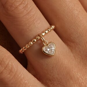 Verfijnde gouden ring met kraaltjes in de vorm van een hartje, minimalistische ring met zirkonia en diamanten.