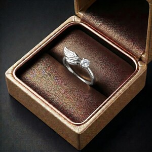 Silver angel wing diamond ring displayed in a luxury brown satin Jewelry box, featuring a detailed wing design beside a round centre stone on a slim polished silver band. A beautiful ring for promise, anniversary, bridal Jewelry, daily wear, angel inspired Jewelry, and fine Jewelry gifting. Perfect for buyers looking for a silver wing ring with clean sparkle and handmade style.