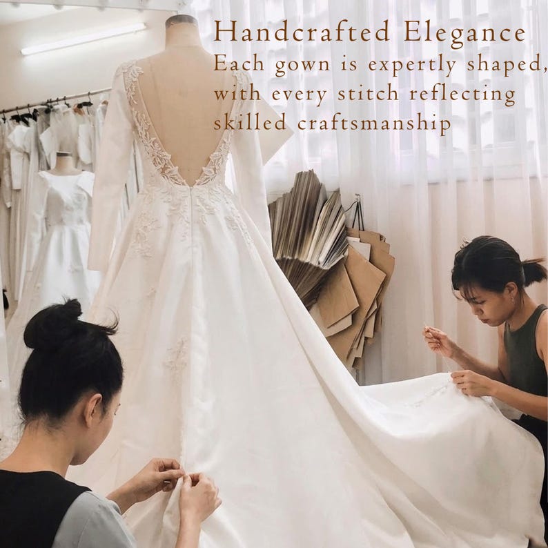 K&ouml;nnte beinhalten: Ein wei&szlig;es lang&auml;rmeliges Kleid mit tiefem V-Ausschnitt am R&uuml;cken, transparenten Eins&auml;tzen und floralen Spitzenapplikationen. Der Text lautet: Handcrafted Elegance. Each gown is expertly shaped, with every stitch reflecting skilled craftsmanship.
