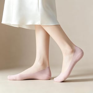 May include: A pair of pale pink no-show socks. The socks are made of a thin, lightweight material and are designed to be invisible when worn with shoes. The socks cover the toes and the ball of the foot, with a low-cut design that sits below the ankle.