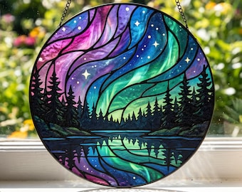 May include: A circular stained glass suncatcher featuring a vibrant aurora borealis sky in shades of purple, blue, and green above a dark silhouette of a pine forest and a reflective lake, suspended by a black metal chain.