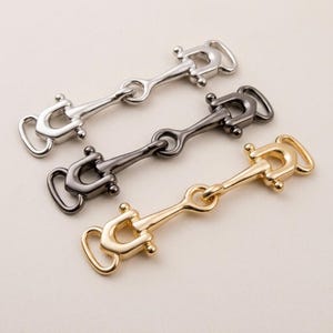 Può includere: Una tazza di ceramica bianca con un manico nero e la scritta "But First, Coffee" in nero, con un carattere a mano. La tazza è su una superficie bianca.