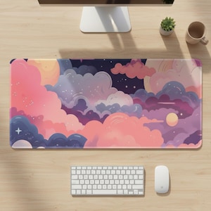 Puede incluir: Alfombrilla de escritorio rectangular con un diseño de paisaje de nubes en tonos rosas, morados y azules. La alfombrilla está colocada sobre un escritorio de madera, con un teclado, un ratón, un monitor de ordenador, una pequeña planta y una taza.