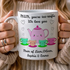 Op de afbeelding: Witte keramische mok met een roze theepot en kopjes ontwerp. De mok heeft de tekst "Mum, you're tea-rrific We love you" en de namen Liam, Oliver, Sophia & Emma.
