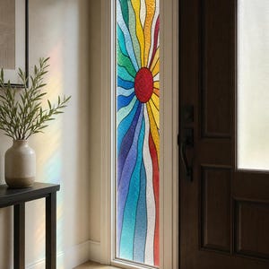 Puede incluir: Una película para ventana alta y estrecha que presenta un diseño vibrante y multicolor de rayos de sol con líneas onduladas en tonos rojo, naranja, amarillo, verde, azul y morado. El patrón irradia desde un centro circular rojo sólido.