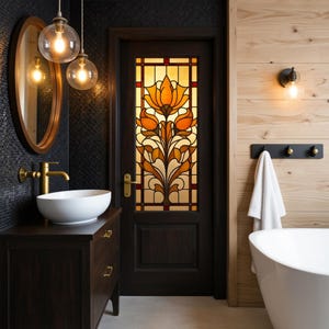 Könnte beinhalten: Badezimmer-Interieur mit dunklem Holzwaschtisch, weißem Waschbecken und goldener Armatur. Eine Buntglastür mit orangefarbenem Blumendesign ist der Blickfang. Der Raum hat eine schwarze Fliesenwand, Holzverkleidung und dekorative Beleuchtung.