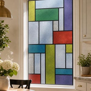 May include: A rectangular window film featuring a geometric grid pattern with various colored panels in red, blue, green, yellow, and purple, separated by thick black lines. The surface has a frosted, textured finish that obscures the view.