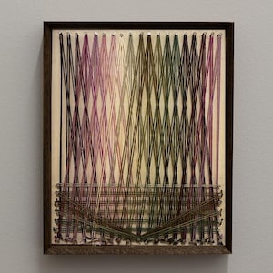 Puede incluir: Una pieza de arte de cuerdas enmarcada con un marco de madera. La obra presenta cuerdas verticales en un degradado de colores, del morado al verde. El texto "Day 3/30" y "BOUND" se muestra en negro.