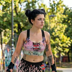 May include: A matching athletic set consisting of a racerback sports bra and fitted shorts, both featuring a pink and white chain-link fence pattern overlaid with black flame graphics, red heart motifs, and the text "Punk" and "Angel" in script.