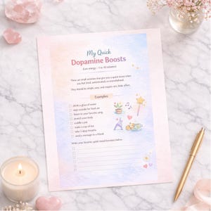 Può includere: Un foglio stampato intitolato "My Quick Dopamine Boosts" con un design ad acquerello. Il foglio elenca semplici attività per migliorare l'umore, come bere acqua e ascoltare musica. Una penna d'oro e una candela accesa sono anche nell'immagine.