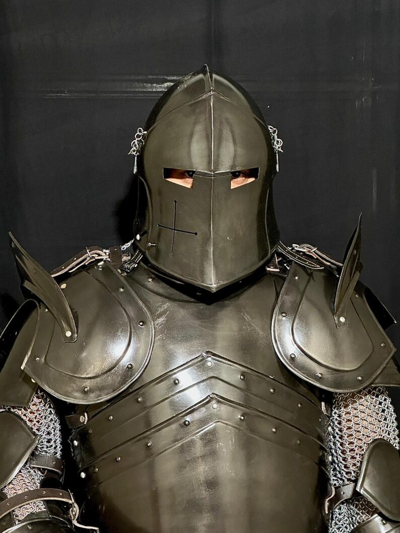 May include: A black knight's armor set, including a helmet with a cross emblem, shoulder guards, and a chest plate. The armor features chainmail and is designed for protection. The helmet has eye slits for visibility.