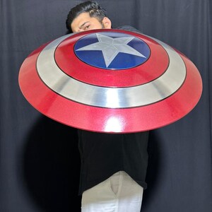 May include: A red, silver, and blue shield with a star in the center. The shield is round and has a metallic finish. The shield is approximately 24 inches in diameter.