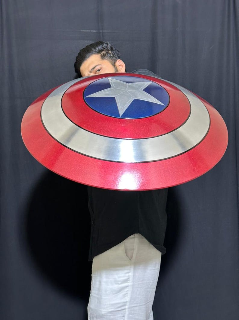 May include: A red, silver, and blue shield with a star in the center. The shield is round and has a metallic finish. The shield is approximately 24 inches in diameter.