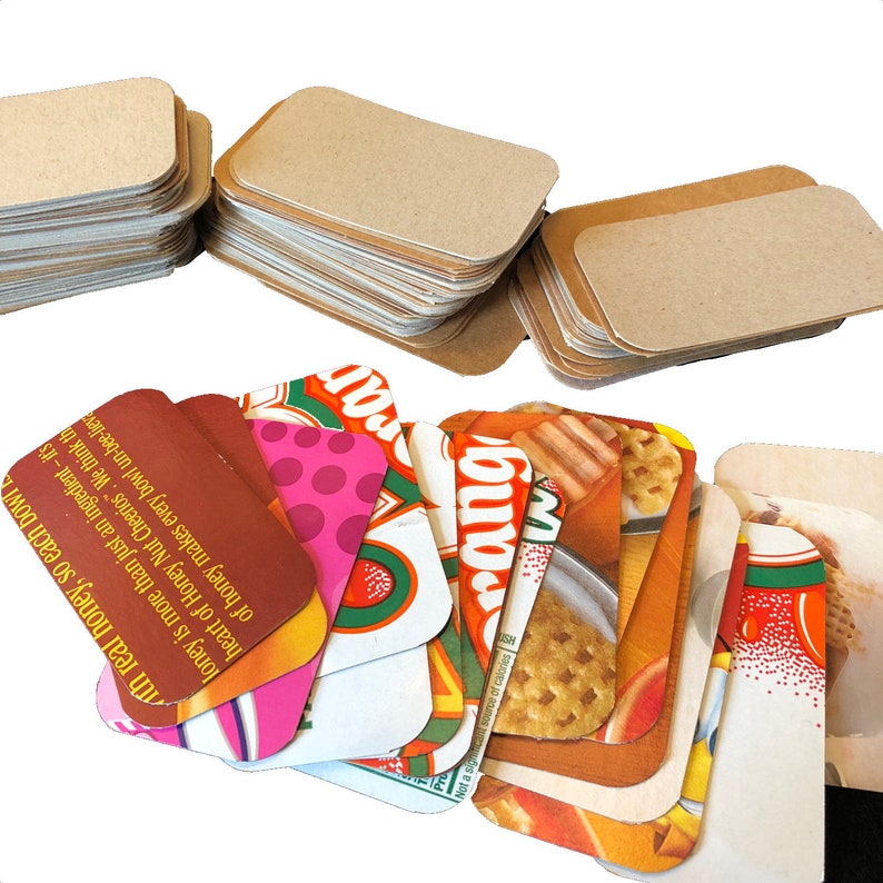 May include: A stack of blank brown cardstock note cards and a stack of colourful cards with images of cereal boxes and the text "Honey Nut Cheerios" and "rang".