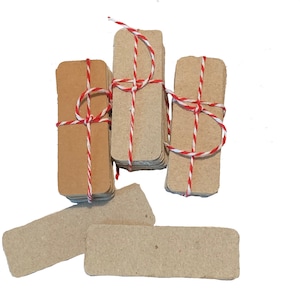 May include: A stack of brown rectangular gift tags tied with red and white twine. There are four stacks of tags and two individual tags.