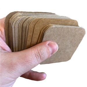 May include: A stack of brown cardboard gift tags with rounded corners. The tags are blank and ready to be written on.